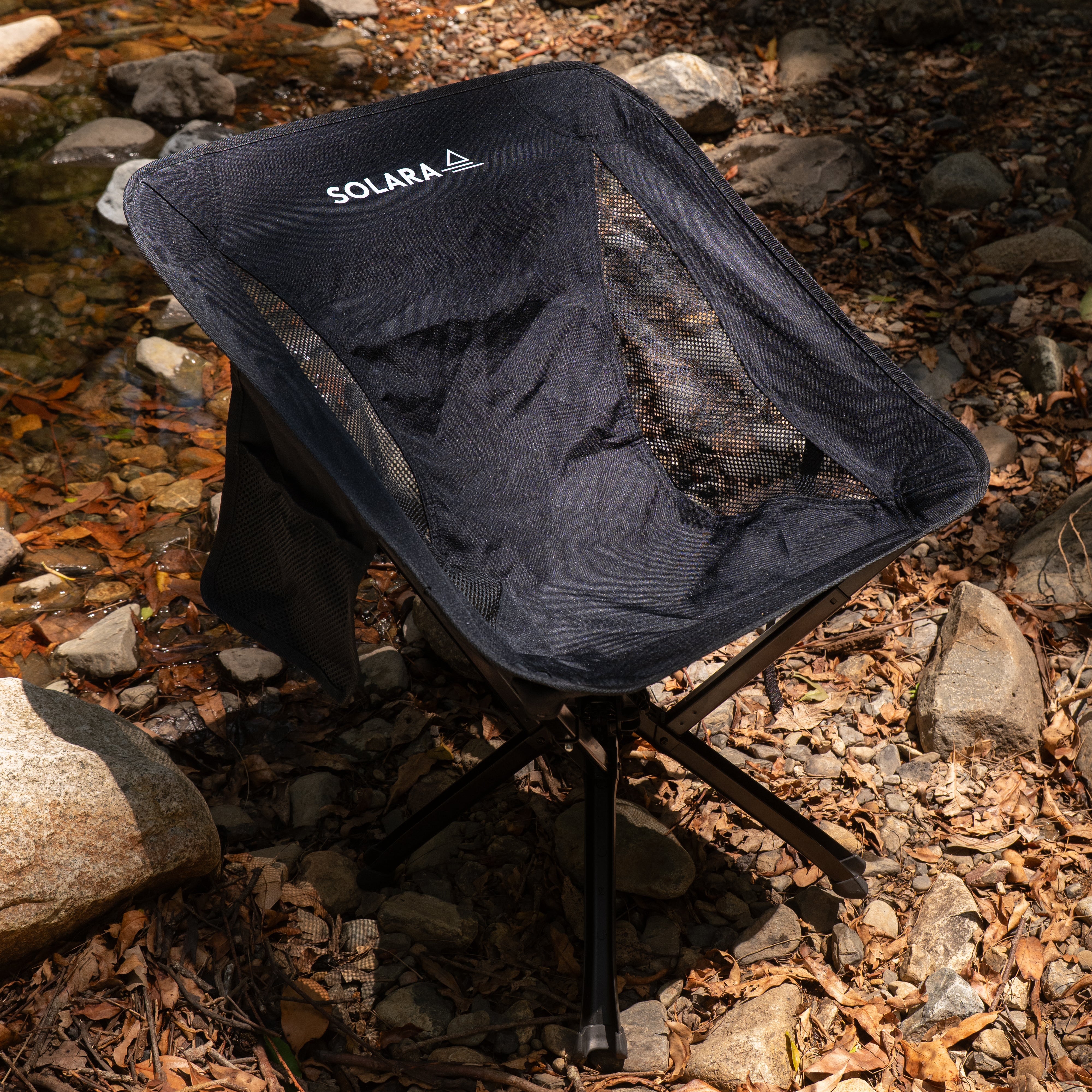 Black camping chair with 'SOLARA' branding on a rocky ground.