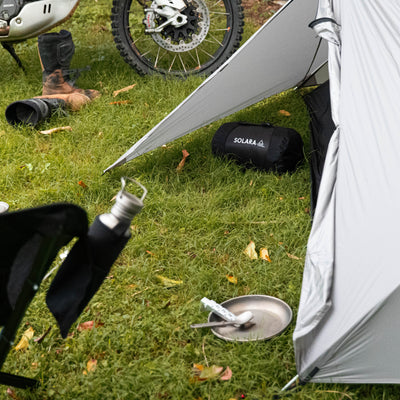 Camping scene with a tent, chair, and camping gear on grass