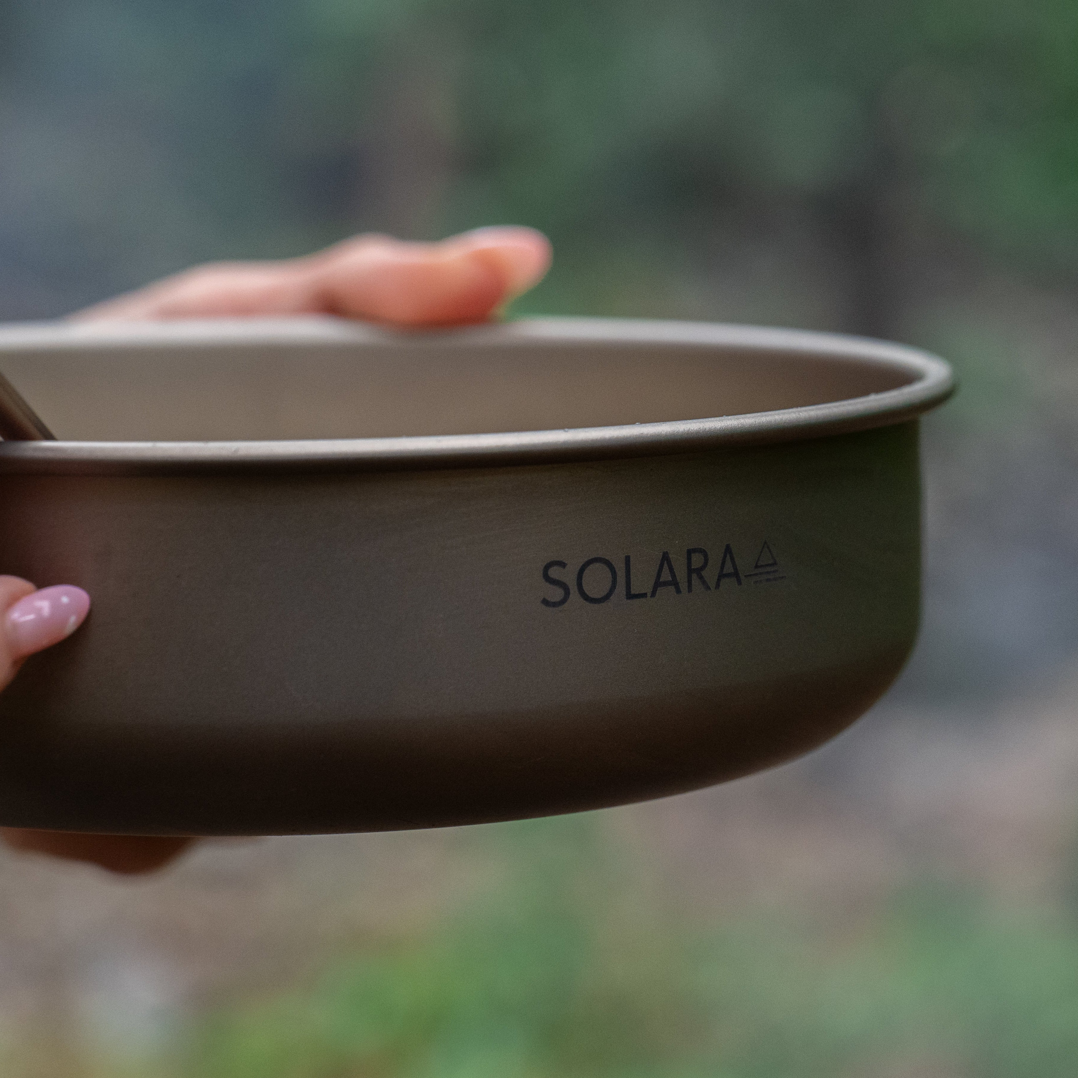Person holding a Solara camping bowl with a blurred natural background