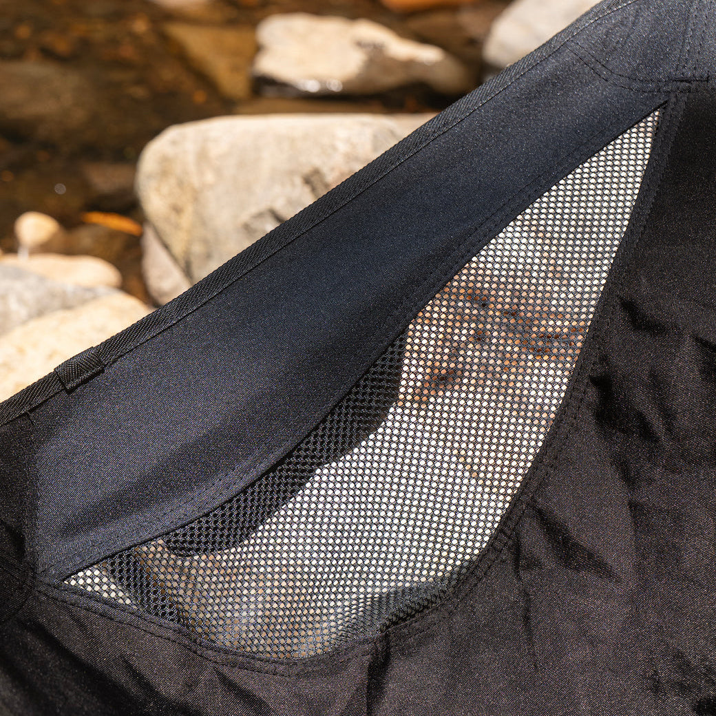 Close-up of a black bag with mesh side, natural stone background