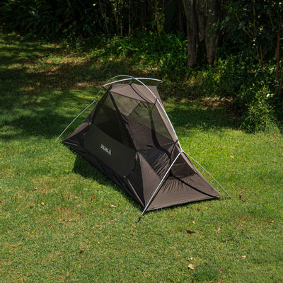 Black camping tent on grass with trees in the background