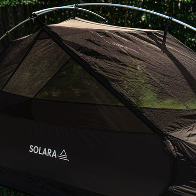 Black and brown tent with 'Solara' branding on grass