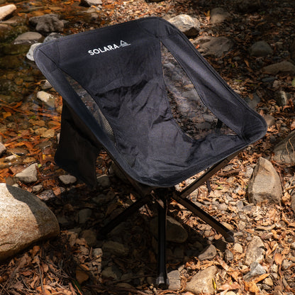 Black camping chair with 'SOLARA' branding on a rocky ground.